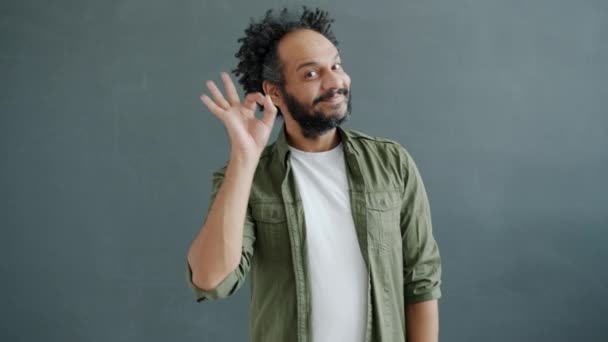 Lassú mozgás portré vidám arab férfi mutatja ok és hüvelykujj-up kéz gesztusok szürke háttér — Stock videók