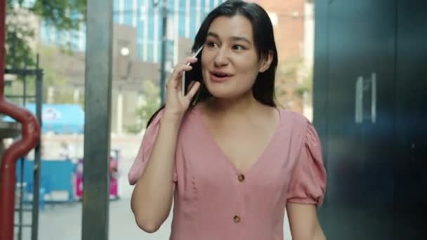 Dolly skott av vacker asiatisk kvinna promenader utomhus talar på mobiltelefon och ler utomhus — Stockvideo