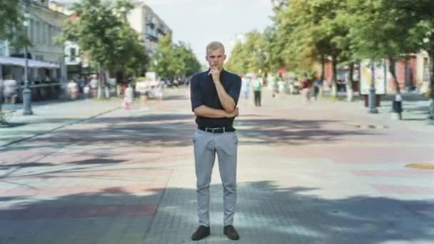 Tid förflutit för attraktiv blond kille står utomhus i upptagen gata med pensiv uttryck och tittar på kameran — Stockvideo