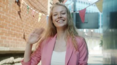 Güzel bir gülümsemeyle el sallayan muhteşem genç bir bayanın ağır çekim portresi.