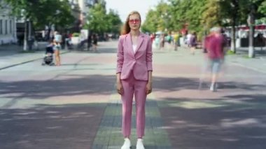 Şık giyinen ve güneş gözlüklü çekici bayanın yoğun caddede dikilirken yakınlaştırma süresi doldu.