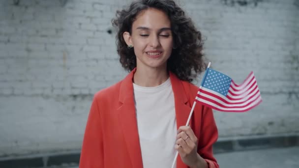 Powolny portret szczęśliwej mieszanej rasy pani trzyma amerykańską flagę narodową uśmiechając się stojąc na zewnątrz — Wideo stockowe