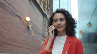 Neşeli kız cep telefonuyla konuşuyor. Gülümsüyor. Açık havada, çıplak bir şekilde gülüyor.
