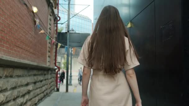 Vista posterior de la hermosa mujer caminando y luego girando a la cámara sonriendo con vestido elegante al aire libre en la calle de la ciudad. — Vídeo de stock