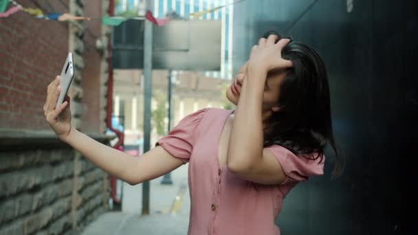 Портрет привлекательной молодой азиатки, делающей селфи со смартфоном на открытом воздухе — стоковое видео
