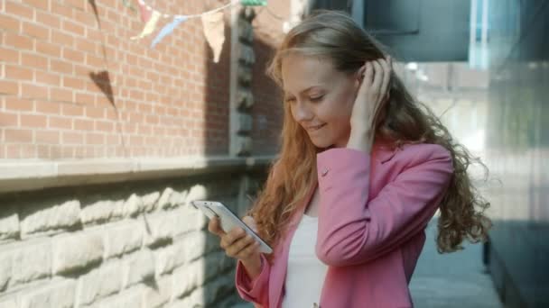Slow motion av vacker dam med smartphone pekskärm skrattar stående i staden — Stockvideo