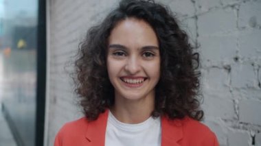 Caddenin dışında kameraya bakarak gülen neşeli bir kadının portresi.