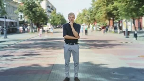 Zoom-in time lapse of pensive guy in elegant clothing standing outside in pedestrian street — Stock Video