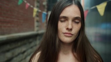 Çekici bir kızın yakın plan portresi. Kameraya bakıyor. Yüzünde sevimli bir gülümseme var.