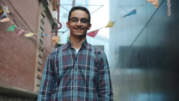 Portret van een aantrekkelijke man uit het Midden-Oosten die met zijn hand zwaait en buiten in de stad lacht — Stockvideo