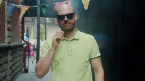 Portret van een knappe man die trendy zonnebrillen opheft en met een serieus gezicht naar de camera kijkt — Stockvideo