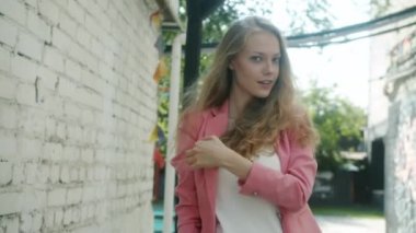 Çekici kız gülümsüyor, flört ediyor, saçlara dokunuyor yaz günü şehir caddesinde duruyor.