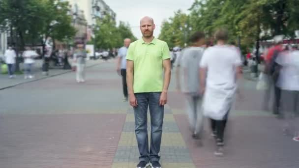 ズームイン時間の経過の深刻な男のカジュアル服の群衆の中に忙しい通りに立って — ストック動画