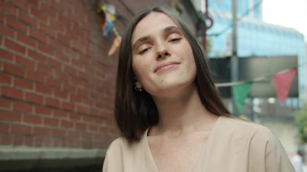 Radosna młoda dama uśmiecha się patrząc w kamerę ze szczęśliwą twarzą stojącą na miejskiej ulicy — Wideo stockowe