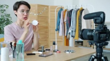 Neşeli genç kadın vlogger kamera kullanarak kozmetik hakkında video kaydediyor