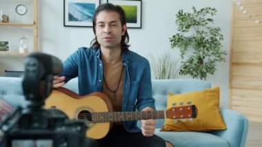 Yaratıcı genç gitarist evde gitar çalan modern kamerayla video kaydediyor.
