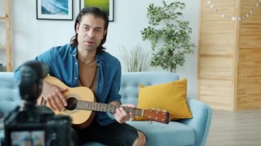 Genç müzisyen video kaydedicisi internet müzik blogu için video kaydediyor gitar çalıyor ve kamera kullanarak konuşuyor