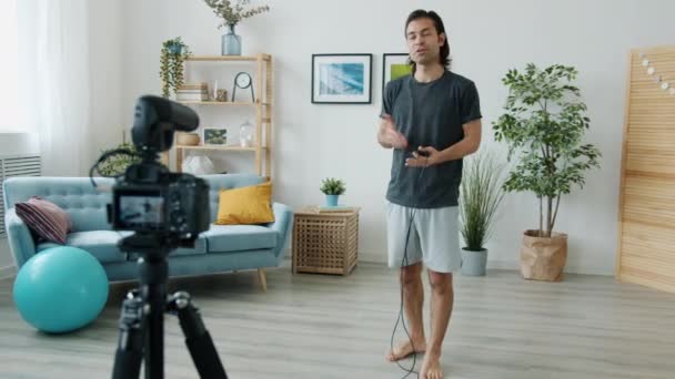 Mixte homme de course sautant sur la corde sautante et enregistrement vidéo pour internet vlog à la maison — Video