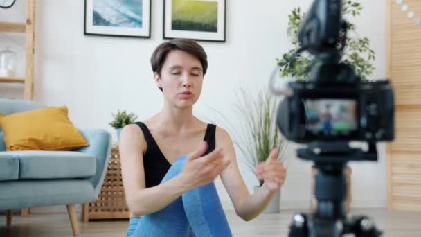 Feminino vlogger falando e fazendo ioga usando câmera dentro de casa no apartamento — Vídeo de Stock
