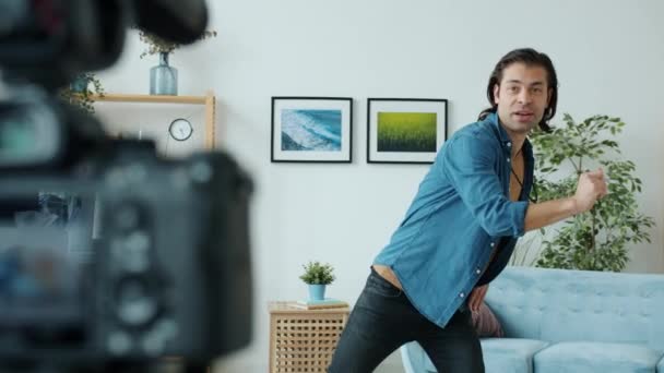 Δημιουργική αρσενικό vlogger καταγραφή χορευτικές κινήσεις και μιλώντας χρησιμοποιώντας κάμερα σε εσωτερικούς χώρους στο διαμέρισμα — Αρχείο Βίντεο