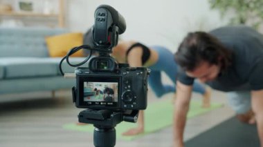 Neşeli çift Asyalı adam ve beyaz kadın evde spor yapıyor ve video kaydediyor.