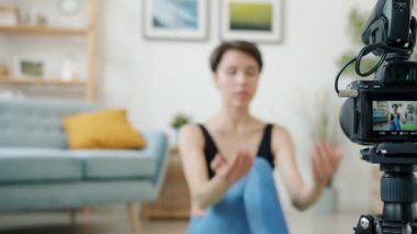 Kamera ekranına yakın çekim ve arka planda yoga yapan genç kadın.