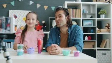 Çocuk ve baba internetteki video bloğu için karışık ırk aile kayıt içeriği akıllı telefon kamerası kullanarak oyun hamuru hakkında konuşuyorlar.