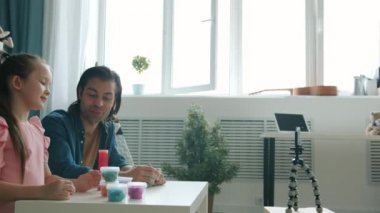 Yaratıcı çocuk ve yetişkin adam akıllı telefon kamerasına bakarak oyun hamuru hakkında video kaydediyor.