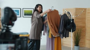 Sosyal medya günlüğü için moda kıyafetleri ve olumlu jestleri gösteren Asyalı kadın vlogger