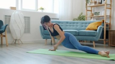 İnce bir kadın internetteki vlog için kamerayla yoga yapıyor ve konuşuyor.