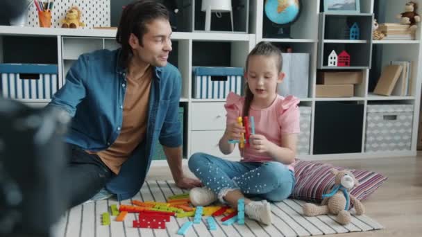 Ayah dan anak keluarga bahagia berbicara tentang mainan yang tertidur sambil bergandengan tangan dan tersenyum sambil merekam video dengan kamera — Stok Video