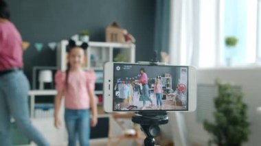 Moda ve giysi hakkında video kaydeden anne ve kız blogcuları gösteren akıllı telefon ekranının yakın çekimi
