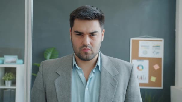 Амбициозный предприниматель, стоящий в офисе в одиночестве и смотрящий в камеру — стоковое видео