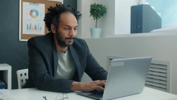Poważny pracownik arabski pracujący z komputerem przenośnym w biurze — Wideo stockowe