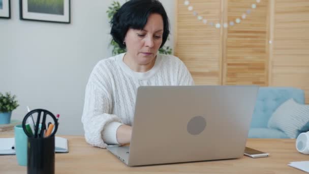 Zmęczona kobieta freelancer pracuje z laptopem wpisując następnie dotykając twarzy uczucie wyczerpania w domu — Wideo stockowe