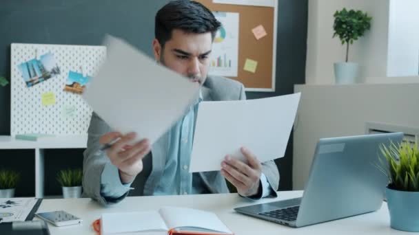 Poważny biznesmen pracujący z dokumentami i piszący przy biurku w biurze — Wideo stockowe