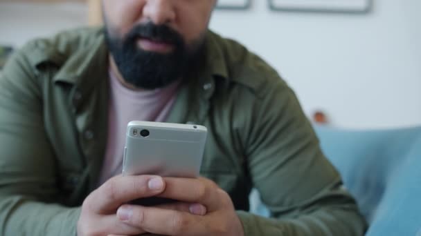 Primer plano de las manos masculinas sosteniendo la pantalla táctil del teléfono inteligente en el interior de la sala de estar — Vídeo de stock