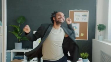Mutlu melez iş adamı işi seviyor break dans yapıyor ve ofiste müzik dinliyor.