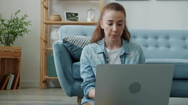 若い女性のフリーランサー作業ノートパソコンの思考で画面を見て自宅で床に座って — ストック動画