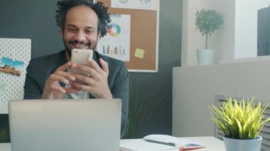 Orta Doğulu işadamı ofiste akıllı telefon kullanarak internet iletişiminin keyfini çıkarıyor