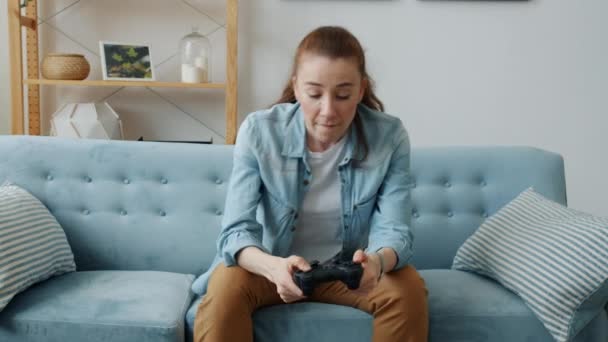 Πορτρέτο της νεαρής κοπέλας απολαμβάνοντας video game στο σπίτι κάθεται στον καναπέ στο μοντέρνο διαμέρισμα — Αρχείο Βίντεο
