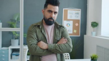 Orta Doğulu yakışıklı bir ofis çalışanının kameraya bakan yavaş çekim portresi.