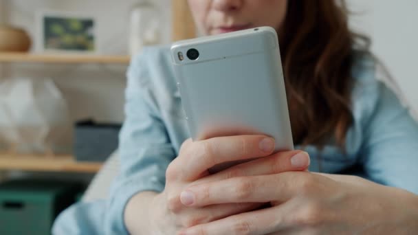Close-up van vrouwelijke handen met behulp van smartphone aanraken scherm, terwijl de vrouw met behulp van apparaat thuis — Stockvideo