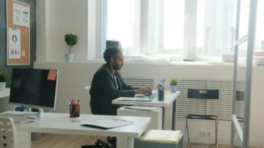Yaratıcı odada dizüstü bilgisayar kullanan ciddi bir erkek ofis çalışanının yan görüntüsü