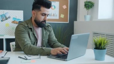 Ciddi melez bir ırk bilgisayarı kullanıyor. Evde tek başına çalışıyor. İşine odaklanmış.