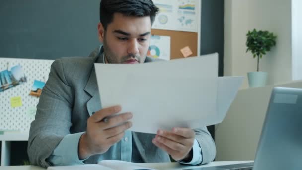 Hırslı işadamı gazete okuyor ve ofiste çalışan iş geliştirme üzerine notlar alıyor. — Stok video
