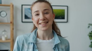 Mutlu genç bayan gülümseyip gülüyor ve modern ışık odasında duran kameraya bakıyor.