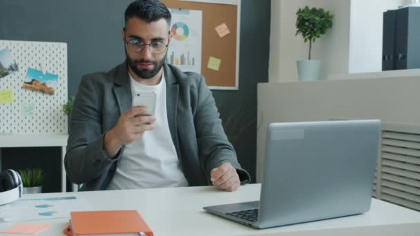 Vreugdevolle zakenman op zoek naar smartphone scherm en het vieren van succes op het werk — Stockvideo