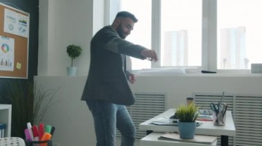 Modern iş yerinde dans eden ve eğlenen yakışıklı iş adamlarının yavaş çekimleri.