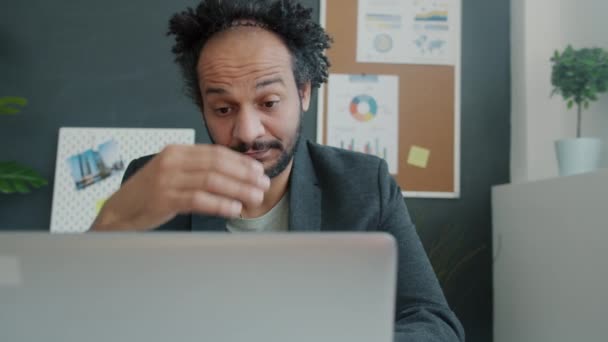 Trabajador de oficina sobrecargado usando computadora portátil y tocando la cabeza sufriendo de dolor en el lugar de trabajo — Vídeos de Stock